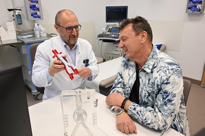 Mit einem Stent kann eine erweiterte Aorta von innen gestützt werden: Dr. Sven Seifert zeigt seinem Patienten Kai Schmidt an einem Model, wie das funktioniert.