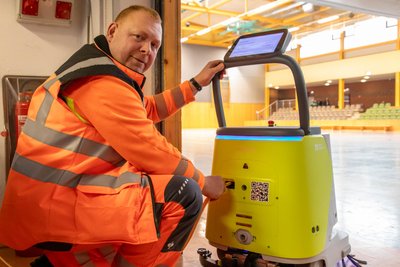 Der Energietechniker Heiko Schober lädt in der Turnhalle Reinigungsroboter Pudu für seinen nächsten Nachteinsatz auf.