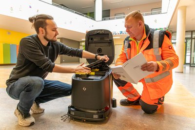 Grundschule Burkhardtsdorf: Robyn Leihbecher von TCO robotics GmbH (links) und Heiko Schober richten den Reinigungsroboter Phantas ein.