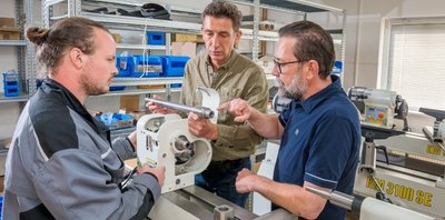 Robin Leonhardt bespricht mit Roland und Martin Steinert (v. l.) bei der Montage einer Drechselbank ein technisches Detail. 
