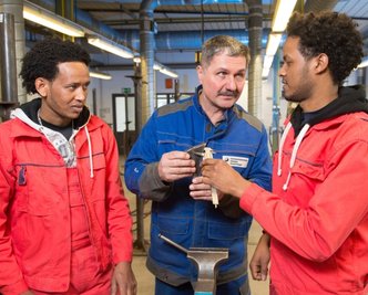 Schweißlehrer Harald Mogel (Mitte) erklärt Awet Afewerki (l.) und Esmael Mahmud, die aus Eritrea nach Dresden geflüchtet sind, das Handwerk.