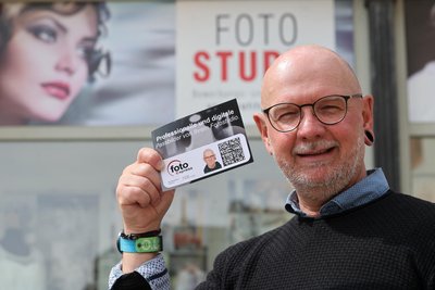 René Abshagen präsentiert vor seinem Geschäft am Altmarkt die Karte mit dem QR-Code für digitale Fotos, die bei der Behörde zum Auslesen vorgelegt werden muss.