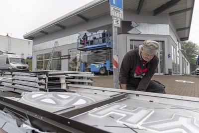 In den Tagen vor der Eröffnung gab es noch viel zu tun. Auch die neue Lichtwerbung war am Autohaus zu montieren - im Ronald Midon.