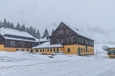 Der Berggasthof „Neues Haus“ liegt direkt an der B 95 am Abzweig zum Grenzübergang nach Tschechien. Laut dem vorherigen Besitzer, Mario Groth aus Oberwiesenthal, wurde der vordere Teil circa um 1820 gebaut.