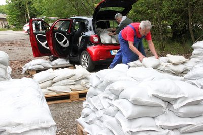 In Plauen bereiten sich Bewohner am Freitag auf den angekündigten Starkregen vor und laden Sandsäcke in ihr Auto.