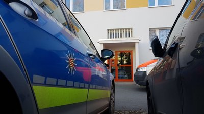 Einsatzkräfte am Eingang zum Wohnhaus an der Straße der Deutschen Einheit.