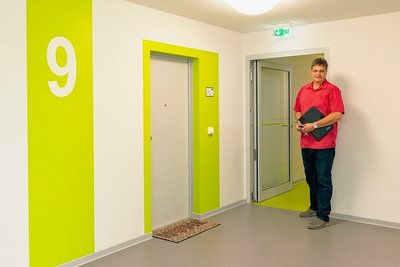Der neue Fahrstuhl-Flur, der zu den Wohnungszugängen führt. WVBG-Geschäftsführer Frank Böttcher steht an einer der neuen Brandschutztüren.