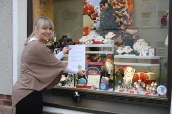 2G: Neue Regeln - alte Sorgen - Yvonne Limbach vom Juweliergeschäft Bauer in Flöha bringt ein Hinweisblatt mit den 2G-Regeln an ihrem Schaufenster an. Foto: Claudia Dohle