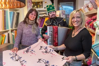 Der Einkauf von Bianca Oertel (l.) im Stoffladen von Annett Voigt (r.) wurde von Thomas Haubold, der in Bergmannstracht Akkordeon spielte, musikalisch umrahmt.