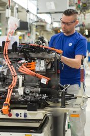 Ein Mitarbeiter befestigt in Wolfsburg ein Bauteil an einem Motorblock. Teile der Belegschaft wird VW wohl in Kurzarbeit schicken.