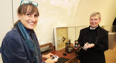 Ausstellungsgestalterin Kirsten Helmstedt (l.) und Museumsdirektorin Andrea Riedel an einem historischen Arbeitstisch, der in der neuen Sonderausstellung zur Geschichte der Freiberger Präzisionsmechanik. 