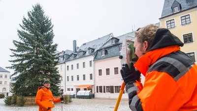 Vermessungsingenieur Detlef Wuttke (links) und Auszubildender Paul Neyen nehmen beim Schneeberger Weihnachtsbaum Maß. 