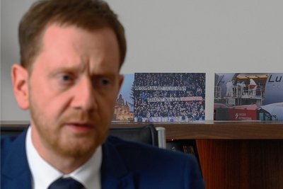 Sachsens Ministerpräsident Michael Kretschmer (CDU) beim Interviewtermin vor aufgestellten Fotos mit Szenen der Coronapandemie. 