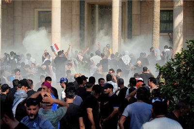 In Tränengaswolken gehüllt, protestieren Anhänger des Schiitenführers Muktada al-Sadr vor dem Regierungspalast in Bagdad. Sadr rief seine Gefolgsleute inzwischen von der Straße zurück. 