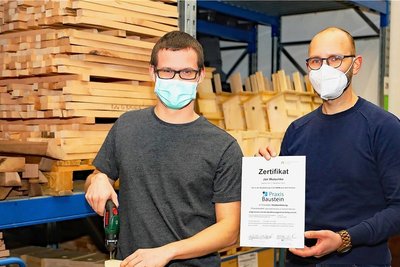 Jan Wutschke (links) freut sich über sein Zertifikat im Praxisbaustein Holz, das ihm sein Ausbilder Christian Röhnert (rechts) übergab. 