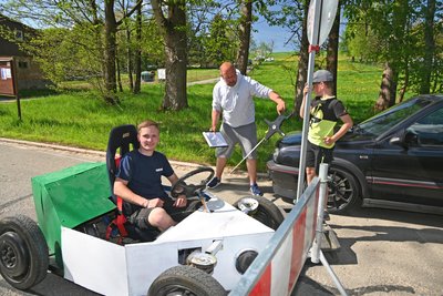 René Seidel am Endpunkt der Strecke beim Seifenkistenrennen in Kleinhartmannsdorf - und damit Sieger. Schiedsrichter Volker Urbansky misst 96 Meter.
