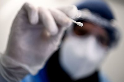 Ein Arzt hält ein Teststäbchen für die Entnahme einer Probe für einen Corona-Test in der Hand.