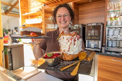 Wer da nicht schwach wird: Vicki Küttner in ihrem Café Balance in Thermalbad Wiesenbad mit einer ihrer selbstgebackenen Torten und ihrer Spezialität: Windbeutel im XL-Format.