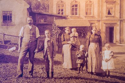 Reproduktion eines historischen Familienporträts vor der Wohnmühle mit Karl an der Hand seines Vaters.