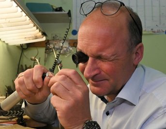 Andreas Lindner, Inhaber von "Juwelier Uhlmann", nimmt das neueste Stück aus der Zwickau-Kollektion unter dieLupe. Er hat es fertigen lassen, weil er seine Stadt gern mag. 