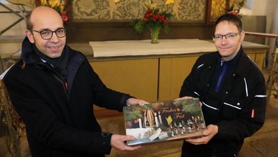 Pfarrer Christian Schubert (l.) überreichte Kirchner Jörg Windisch einen Dankeschönstollen aus der Bäckerei Müller in Breitenbrunn. 