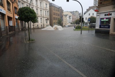 Ein Auto auf der überfluteten Bahnhofstraße in Aue sorgte für eine große Fontäne.