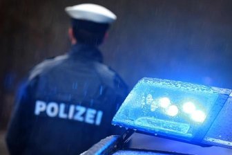 Ein Polizist steht vor einem Streifenwagen.