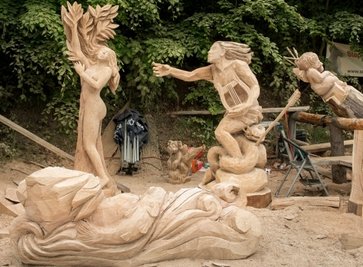 Sonnabend: Die vier Figuren der Gruppe sind fast fertig. Links Daphne, rechts Apollon, der zum Gedenken an seine Geliebte eine mit Lorbeer geschmückte Leier trägt. Vorn liegt Peneios, vom Flusswasser umspielt, darin schwimmen Fische. Rechts hinten: Liebesgott Eros mit seinen Pfeilen. Nur noch Kleinigkeiten müssen gesägt und die Gruppe muss arrangiert werden.