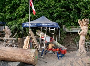 Freitag: Zwei der vier Skulpturen stehen bereits fertig da. Stephanie Huber und Edith Plazotta haben sich die Stämme für Eros bereitgelegt, der einen Liebespfeil auf Apollon abgefeuert hatte und einen Pfeil auf Daphne. Der machte sie unempfänglich für die Liebe Apollons. Vorn liegt ein Stamm für den Flussgott Peneios. Der wird seine Tochter Daphne in einen Lorbeerbaum verwandeln.