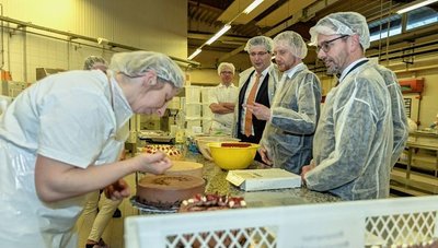 Konditorin Bianca Banofski beim kunstvollen Verzieren einer Torte. Davon angetan waren neben Michael Kretschmer auch CDU-Kreischef Sören Voigt (vorn) und Vogtland-Landrat Thomas Hennig. 