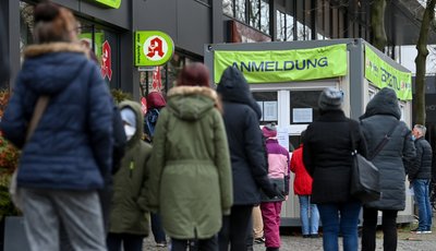 Besucher der Innenstadt warten an einer Corona-Teststation.