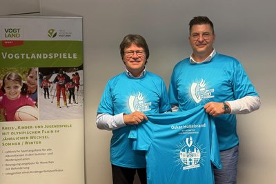 Landrat Thomas Hennig (rechts) und der Präsident des Kreissportbundes Vogtland, Steffen Fugmann, präsentieren den sportlichen Botschafter der 15. Vogtlandspiele, Oskar Hüllebrand.
