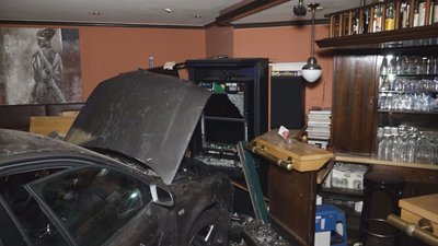 Ein PKW steht nach einem Unfall vor einer Kneipen-Bar.