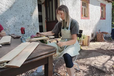 Architekturstudentin Annabelle Heddergott bearbeitet eine Holzschindel mit dem Zieheisen.