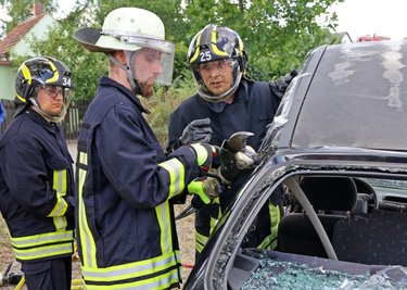 Beim Feuerwehrfest am Gerätehaus Niederfrohna konnten Besucher testen, wie man ein Auto mit schwerer Technik aufschneidet. Hier legt sich EricHeinig aus Niederfrohna (Mitte) ins Zeug. Angeleitet und beobachtet wird er vonMartin Jungmann (rechts) und Nathanael Weise.