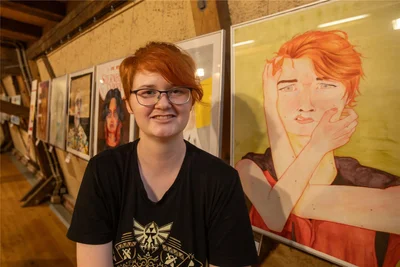 Pauline Helmert vor ihrem Selbstbildnis. Sie scheint sich auf dem Bild die Haare zu raufen und verzerrt etwas die Mundwinkel.