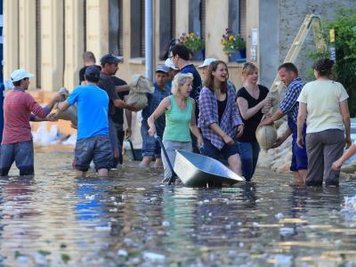 Helfer schichten Sandsäcke in einer überfluteten Straße in Magdeburg gegen das steigende Hochwasser auf.