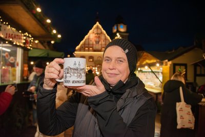 Beate Groh, Hofleiterin vom Plauener Pfaffengut, zeigt den neuen Weihnachtstipfl für das Jahr 2025. Groh nahm stellvertretend für die Stadtfüchsin Plauline, von der der Entwurf stammt, die erste Mustertasse entgegen.