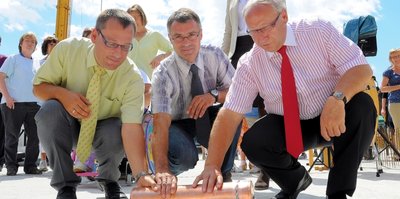 Torsten Stolpmann, Geschäftsführer des Vereins Lebenshilfe, Dezernent Uwe Drechsel und Reichenbachs OB Dieter Kießling (von links) haben am Dienstag eine Kupferhülse, die auch die "Freie Presse" enthält, im Fundament versenkt.