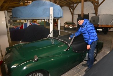 Michael Lienemann mit seinem Triumph TR 3. Wie dahinter zu sehen, kann per Hebebühne auch ein Auto über dem anderen parken. Theoretisch würden sogar drei Fahrzeuge übereinander passen: Die Halle ist acht Meter hoch.