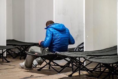 Ein Wohnungsloser macht sich in einer Notunterkunft auf einem Feldbett bereit für die Nacht.