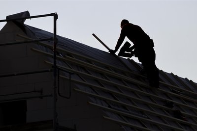 Ein Dachdecker arbeitet auf einem Einfamilienhaus: Bei den aktuell hochsommerlichen Temperaturen ist das eine echte Schweißarbeit.