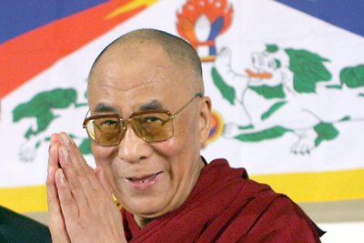 Das geistige Oberhaupt der Tibeter, Dalai Lama, vor der Tibet-Flagge.