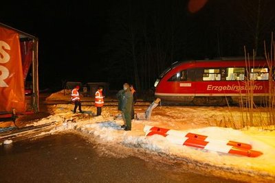 
              <p class="artikelinhalt">Ein Polizist sichert Spuren des Unfalls. Der Bahntriebwagen war in den Anhänger gerast und hatte ihn gegen die Schranken gedrückt.</p>
            