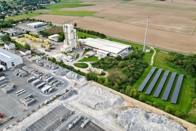 Ein Drohnenbild gibt einen Überblick über das Firmengelände Sakret in Diethensdorf mit markantem Turm, Fotovoltaikanlage und vielen Grünflächen.