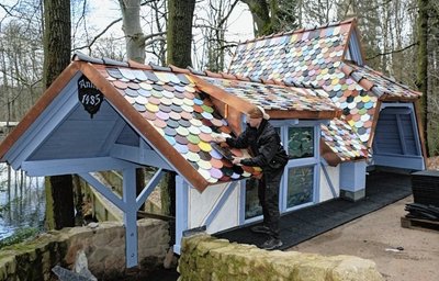 Marco Wilhelm bringt die letzten bunten Dachziegel am rekonstruierten Märchen-Häuschen "Knüppel aus dem Sack" an.
