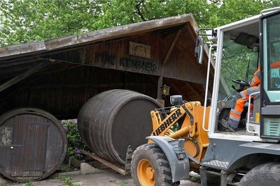 Ein Radlader hebt eines der vier Riesenfässer vom Berggasthaus vorsichtig hoch. Sie kommen weg. Das Dach darüber ist am Zusammenbrechen. Es ist lange her, dass in den Fässern Gastronomie stattfand. 