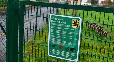 Im Zaun um die Hundewiese gibt es mehrere Schlupflöcher. Ein Schild am Eingang weist Halter auf ihre Aufsichtspflicht hin.
