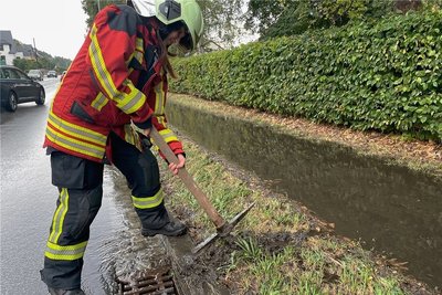 An der B 169 in Bad Schlema griffen Feuerwehrleute zur Hacke, damit Wasser abfließen kann. 