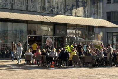 Menschen sitzen in der Sonne und genießen die leckeren Eisspezialitäten bei Ferioli Gelato.